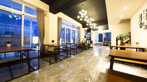 A modern dining area with marble flooring, wooden tables and benches, large windows with curtains, and a ceiling light fixture. - Brother B&B (Magong)