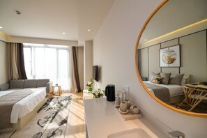 A modern hotel room with a large bed, a sitting area, a small table, a coffee maker, and a mirror reflecting the room. - Suisse Place Shanghai (Shanghai)