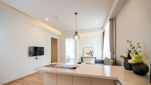 A modern living room with a white reception desk, a flat-screen TV mounted on the wall, and a large window with curtains. - Suisse Place Shanghai (Shanghai)