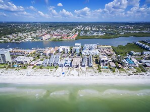 An aerial view of a coastal city with a marina, beachfront hotels, and a mix of residential and commercial buildings. - Water View 103 (Indian Shores)