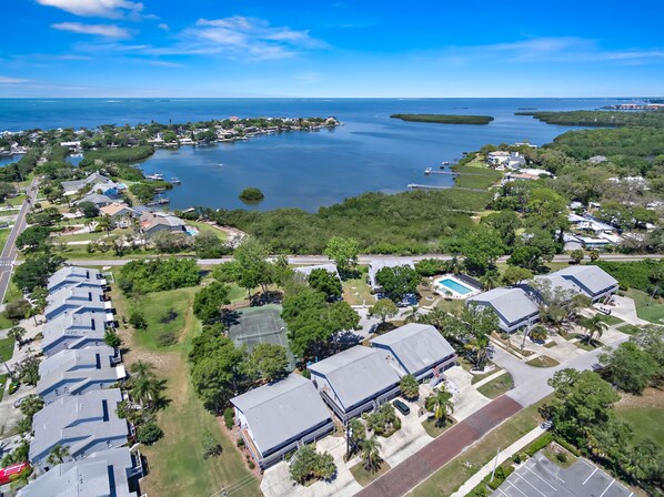Vista aérea de una zona residencial con casas, una cancha de tenis y una gran extensión de agua.