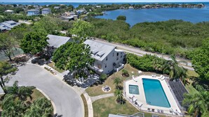 A residential area with a large swimming pool, a road, and a body of water in the background. - Sherwood Lakes A (Palm Harbor)