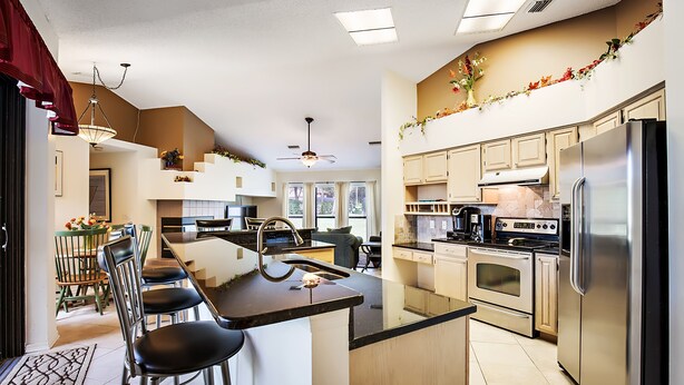Una cocina moderna con una isla central, electrodomésticos de acero inoxidable y un comedor con sillas y mesa.