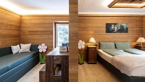 A wooden cabin with a sofa, a wooden table, a bed, and a painting on the wall. - Rifugio Cereda (Primiero San Martino di Castrozza)
