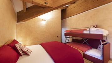 Una habitación con literas, una cama inferior y techo de madera.