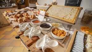 A buffet table with various food items, including pastries, fruits, and condiments. - Rifugio Cereda (Primiero San Martino di Castrozza)