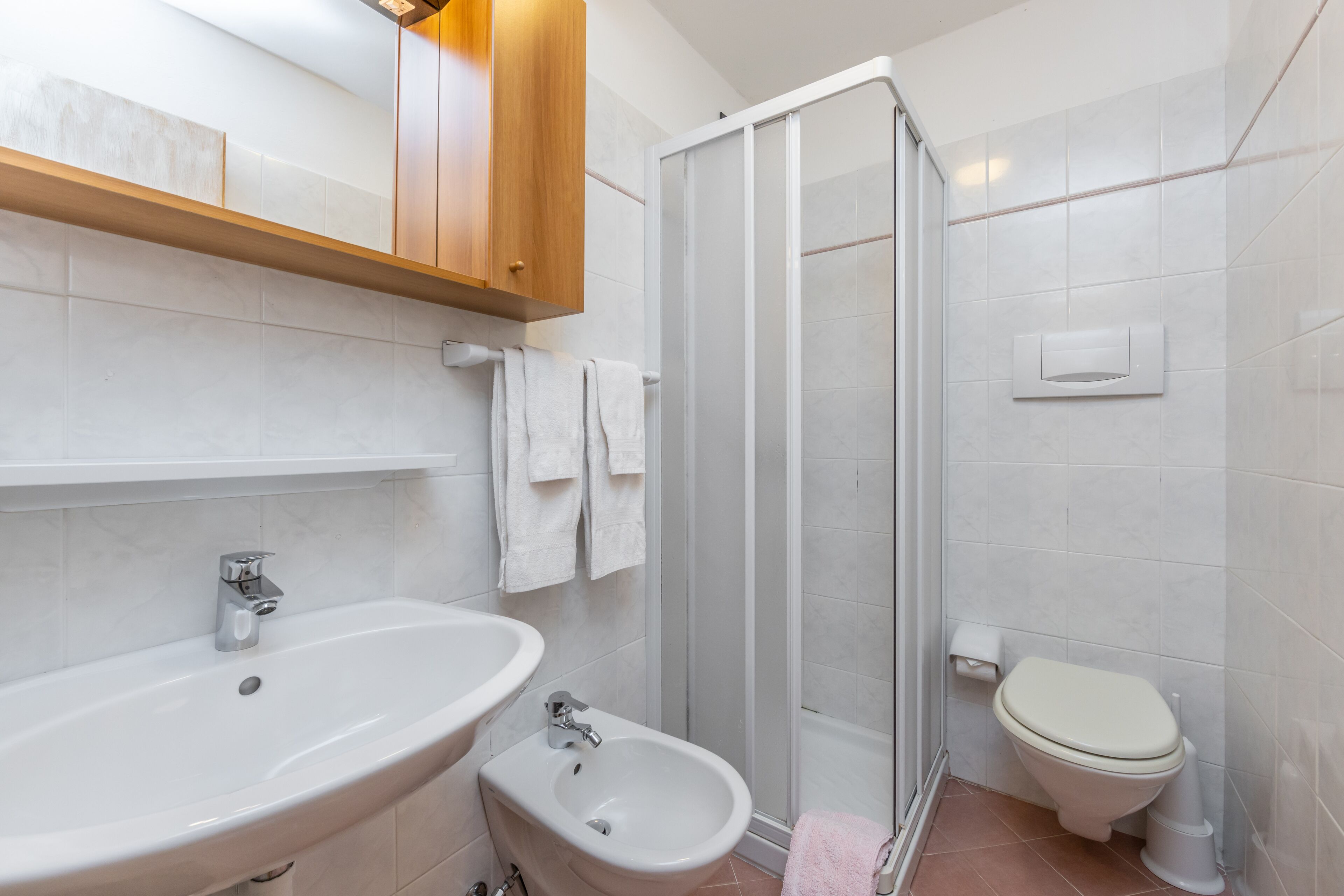 A bathroom with a sink, bidet, toilet, and a glass shower enclosure.