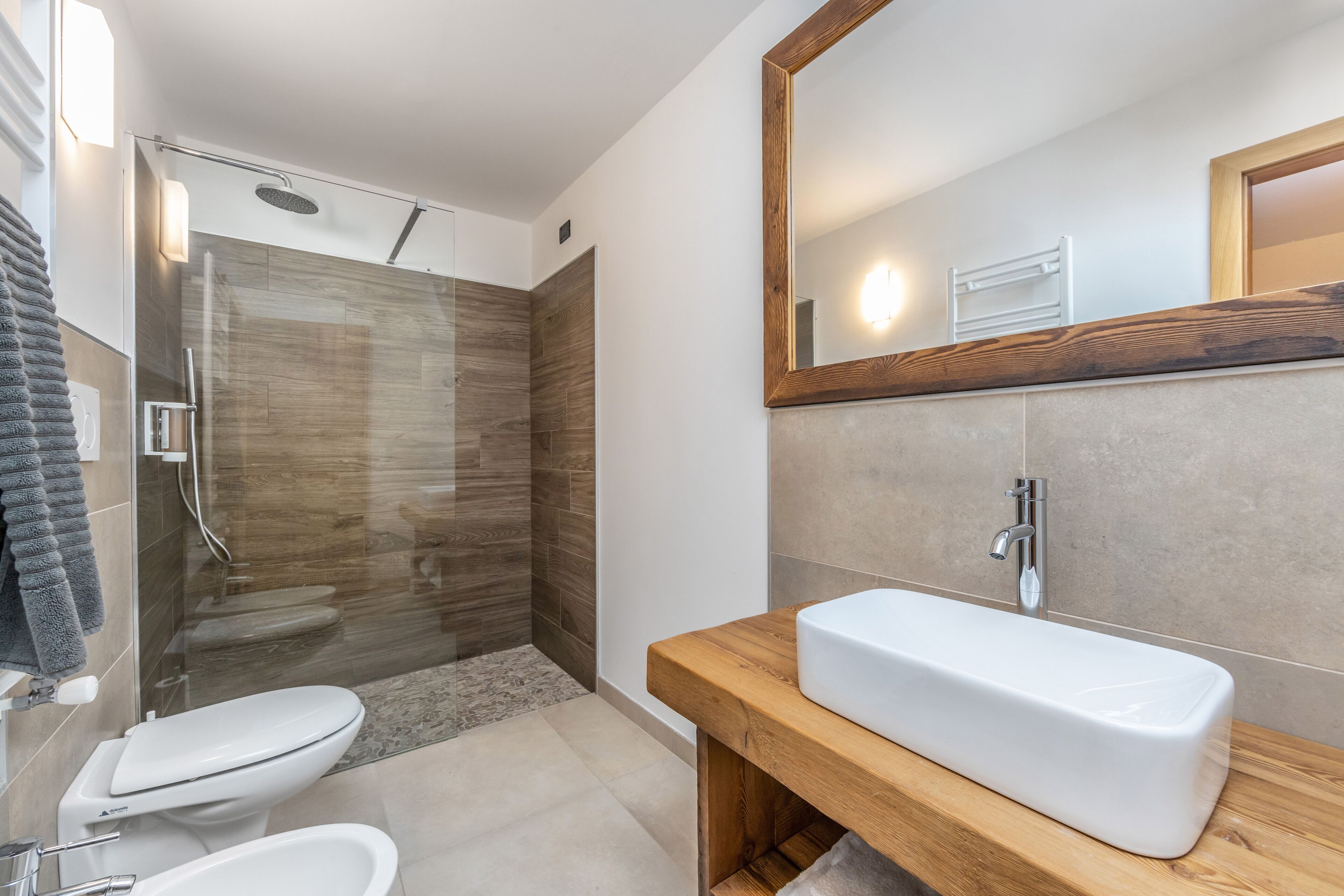 A modern bathroom with a glass-enclosed shower, a wooden vanity, and a large mirror.