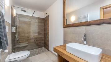 A modern bathroom with a glass-enclosed shower, a wooden vanity, and a large mirror.