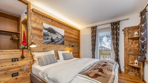 A wooden-paneled bedroom with a bed, pillows, a lamp, and a picture on the wall. - Rifugio Cereda (Primiero San Martino di Castrozza)