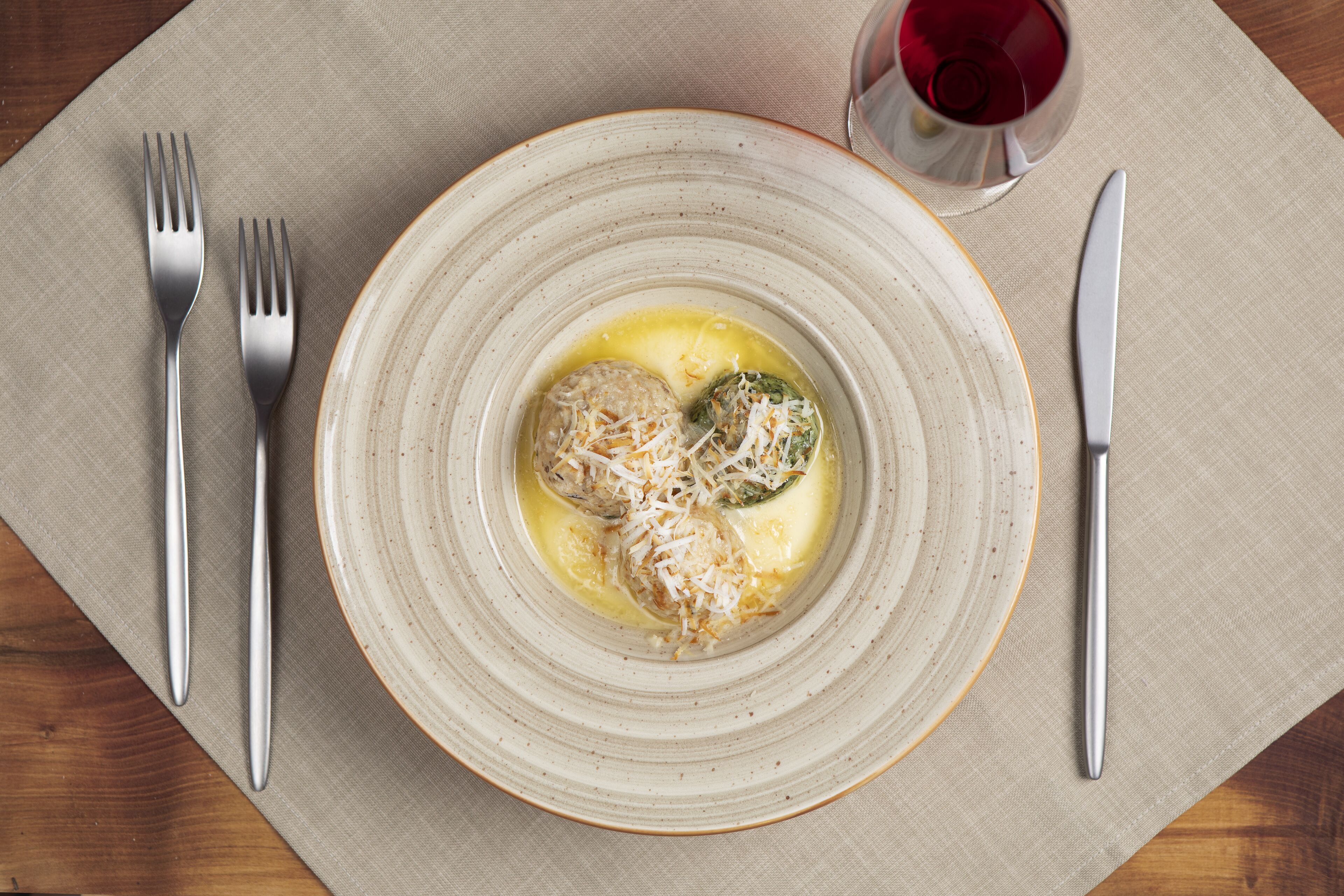 A plate with food and a glass of red wine on a table.