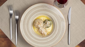 A plate with food and a glass of red wine on a table.