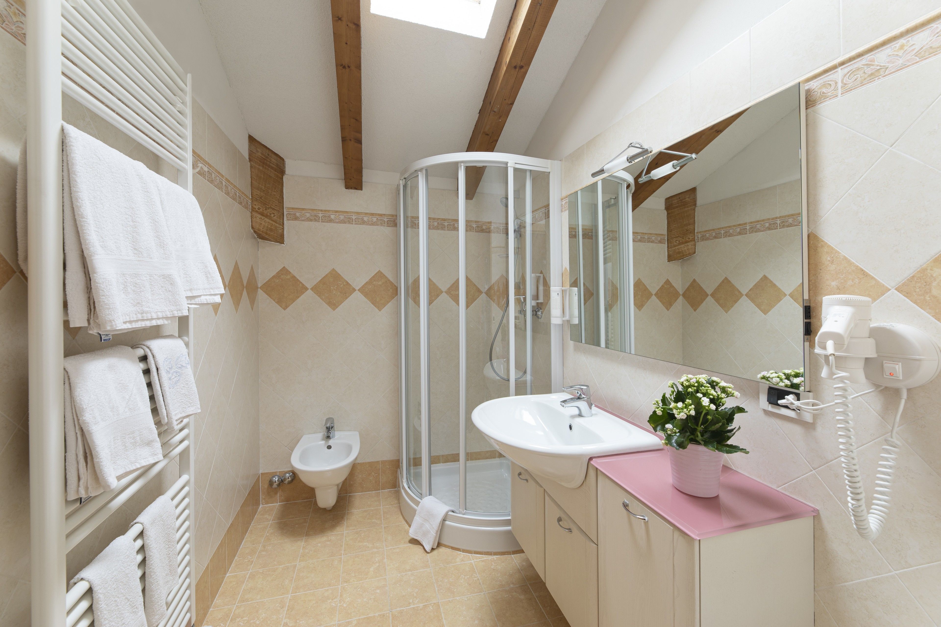A bathroom with a glass-enclosed shower, a sink with a pink countertop, and a bidet.