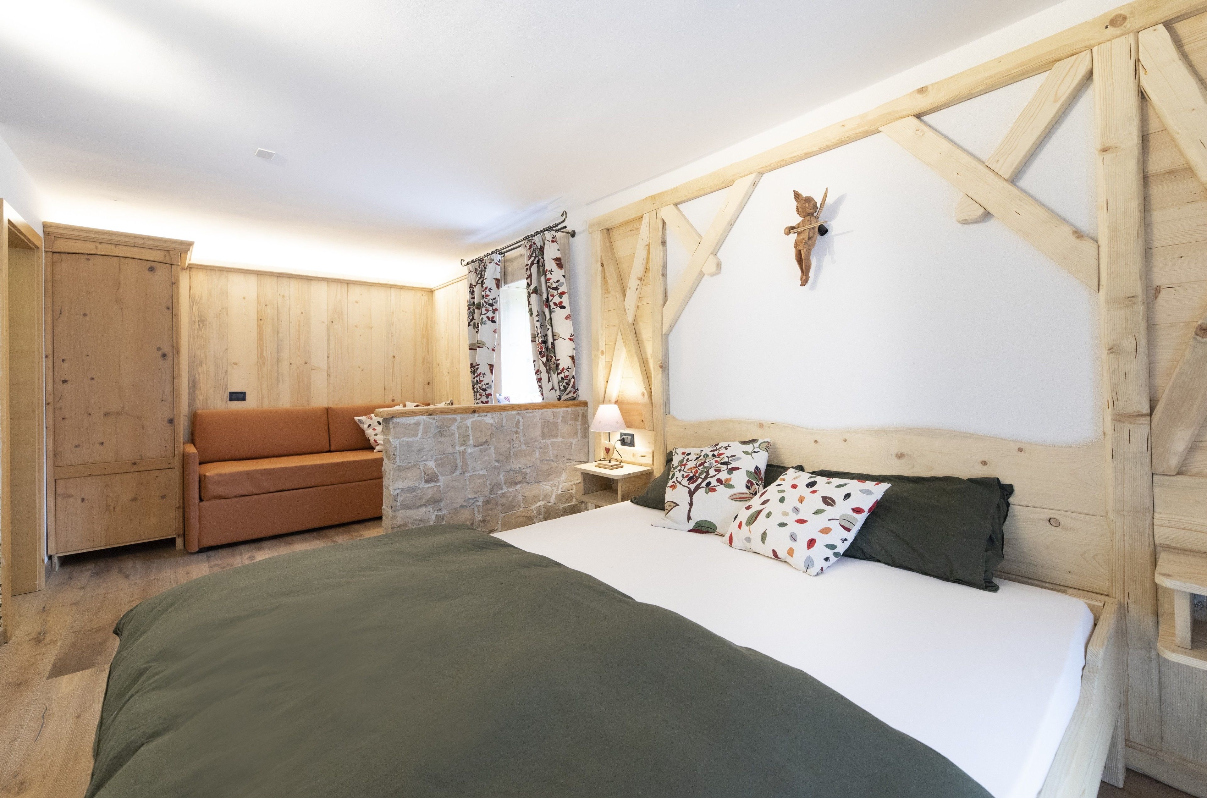 Una camera da letto con un letto e un armadio in legno, un divano e un muro in pietra.