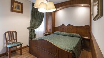 Ein Schlafzimmer mit einem hölzernen Bett, einem Sessel und einer Pendelleuchte.