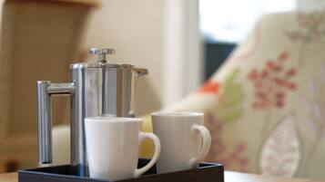 A coffee maker with two white cups on a tray.
