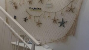 A staircase with a white railing leading to a landing. A small white table with a tissue box is on the landing. - Casa Maritrì (Pachino)