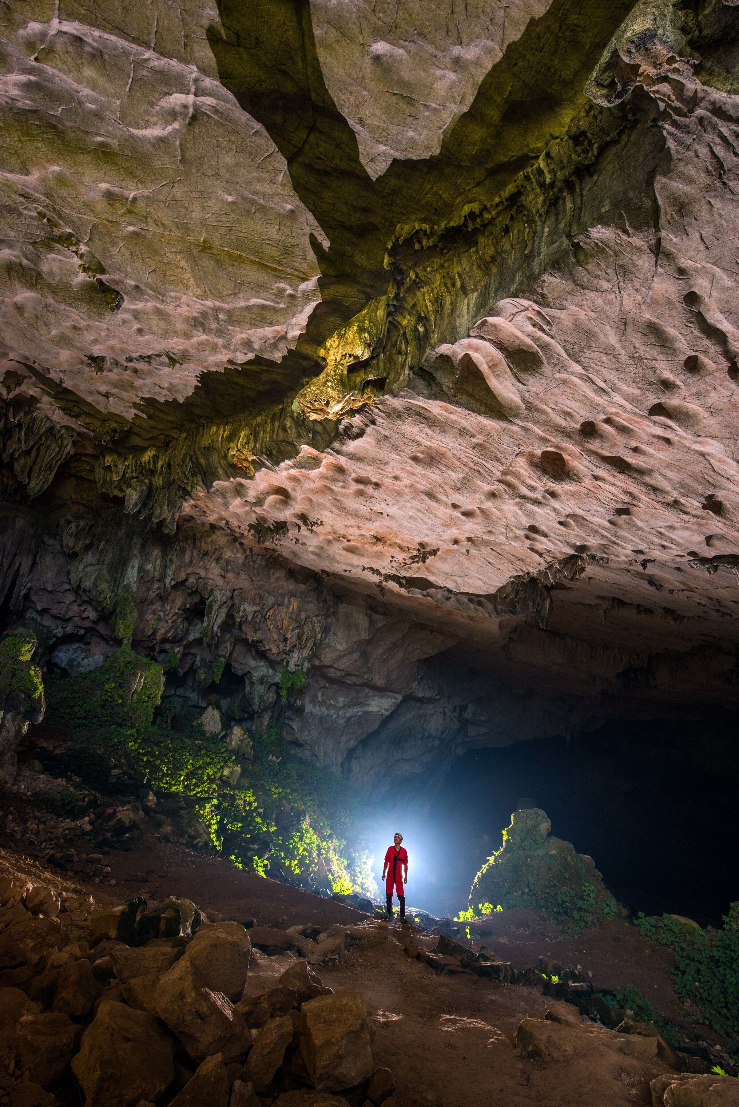 A person standing in a cave with a light source at the end of the cave.