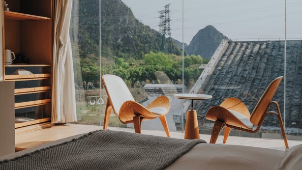 A modern room with a large window, two wooden chairs, a small table, and a built-in wooden shelf with a kettle. - Guilin Bonjour Boutique Hotel (Guilin)