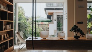 A modern interior with a wooden reception desk, a bookshelf, and a potted plant. - Guilin Bonjour Boutique Hotel (Guilin)