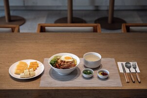 Una mesa de comedor con comida que incluye un tazón de sopa, un plato de fruta y un tazón de ensalada.