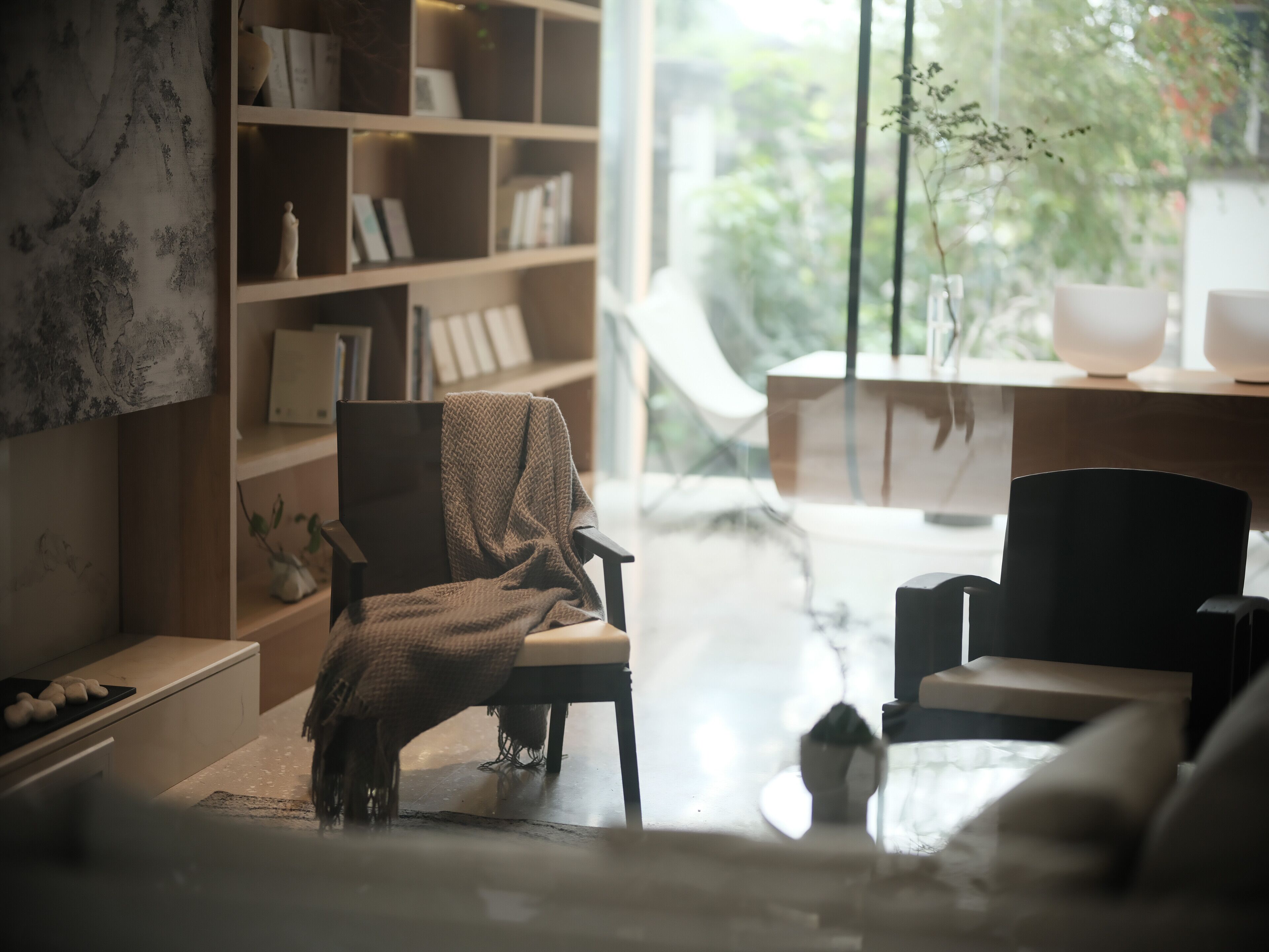 Una sala de estar moderna con un gran ventanal, una estantería y un sillón acogedor.