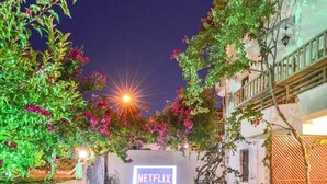 A courtyard with a Netflix sign, a tiled pathway, and colorful cushions on the grass. - Ankakyaka Apart Hotel (Ula)