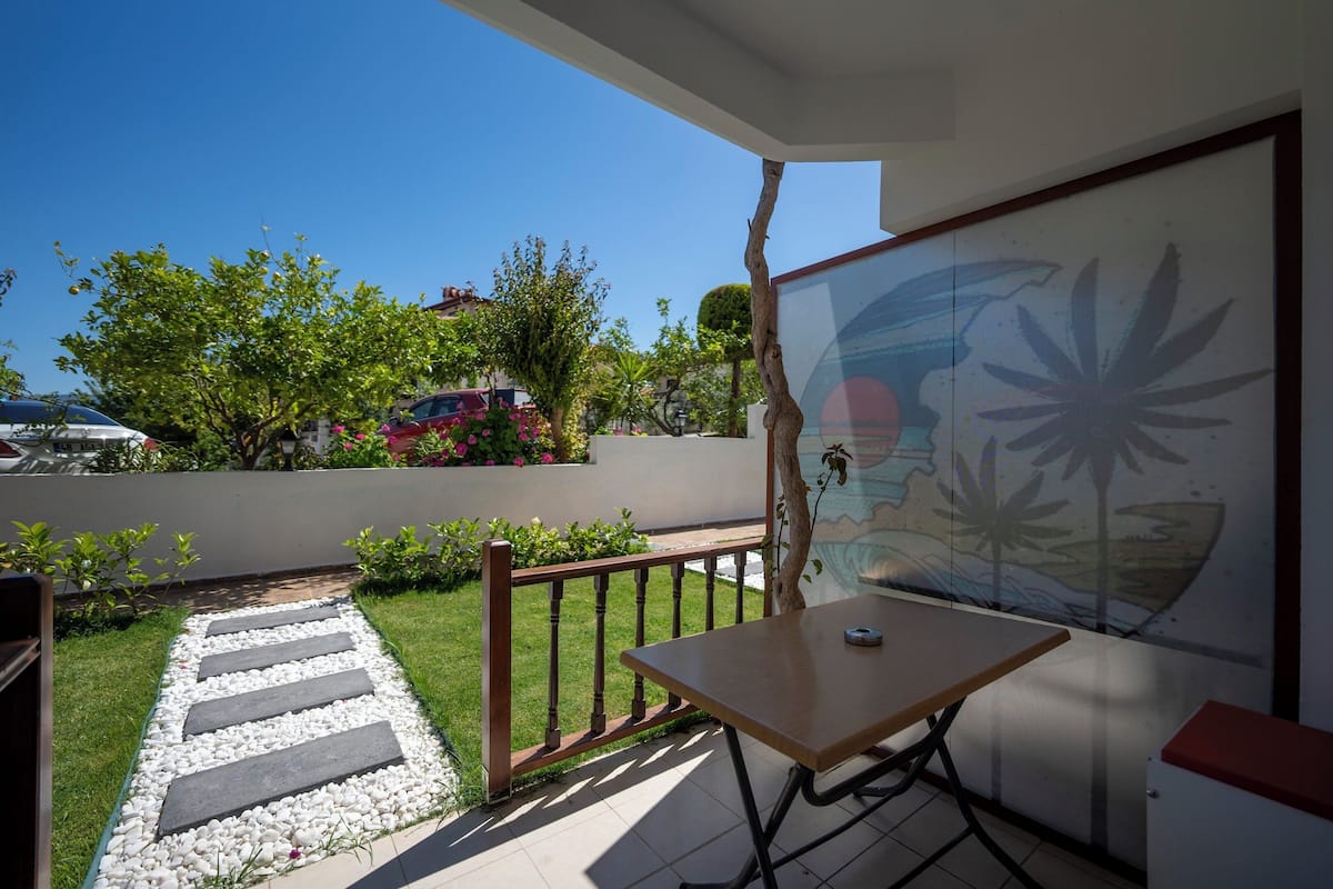 A balcony with a table, a view of the street, and a mural on the wall.