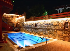 A swimming pool with stone walls and a wooden deck. - Ankakyaka Apart Hotel (Ula)