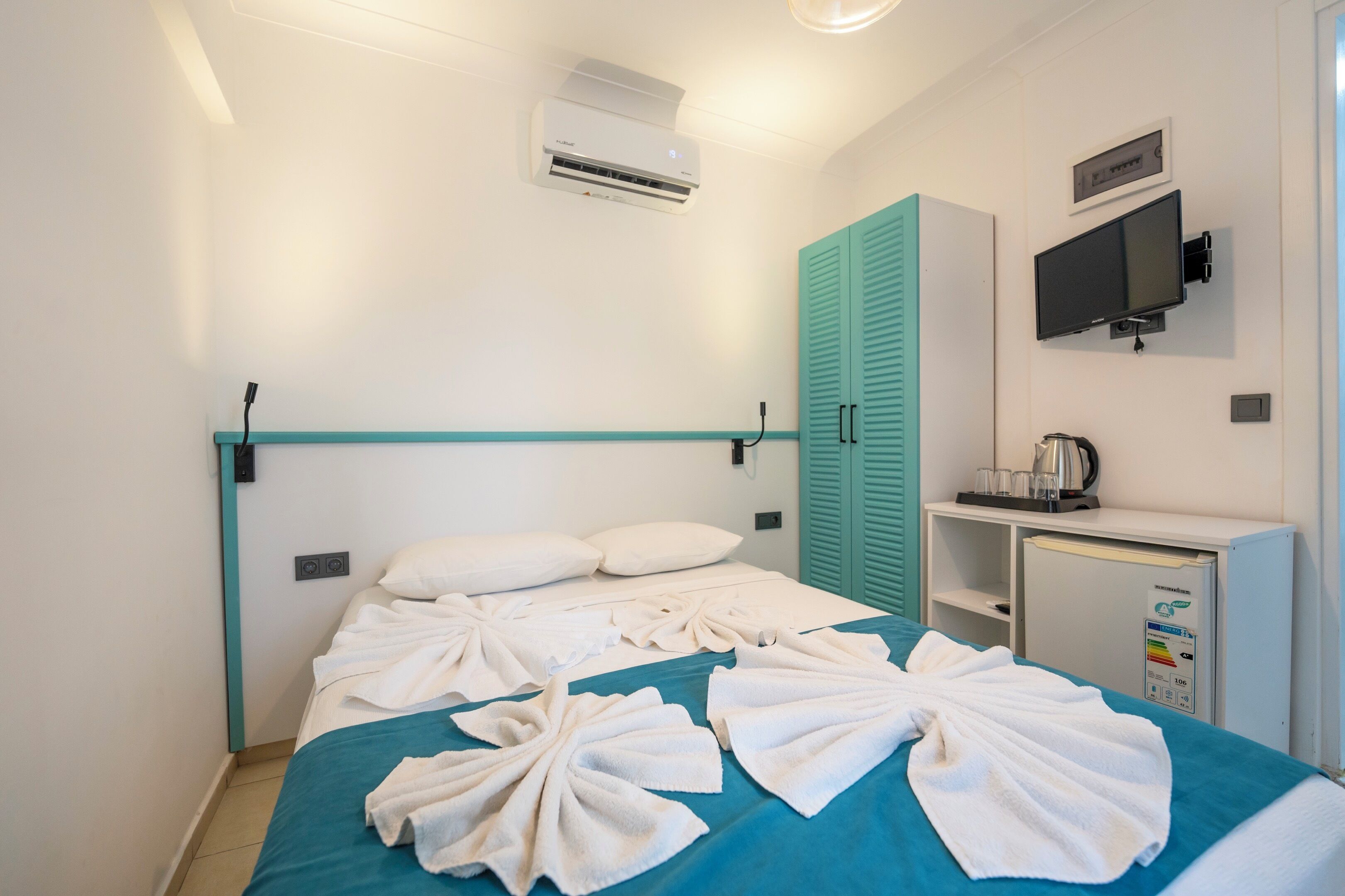 A hotel room with a bed, a desk, a TV, and an air conditioner.