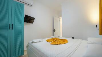 A hotel room with a bed, a TV mounted on the wall, and a wardrobe with sliding doors.