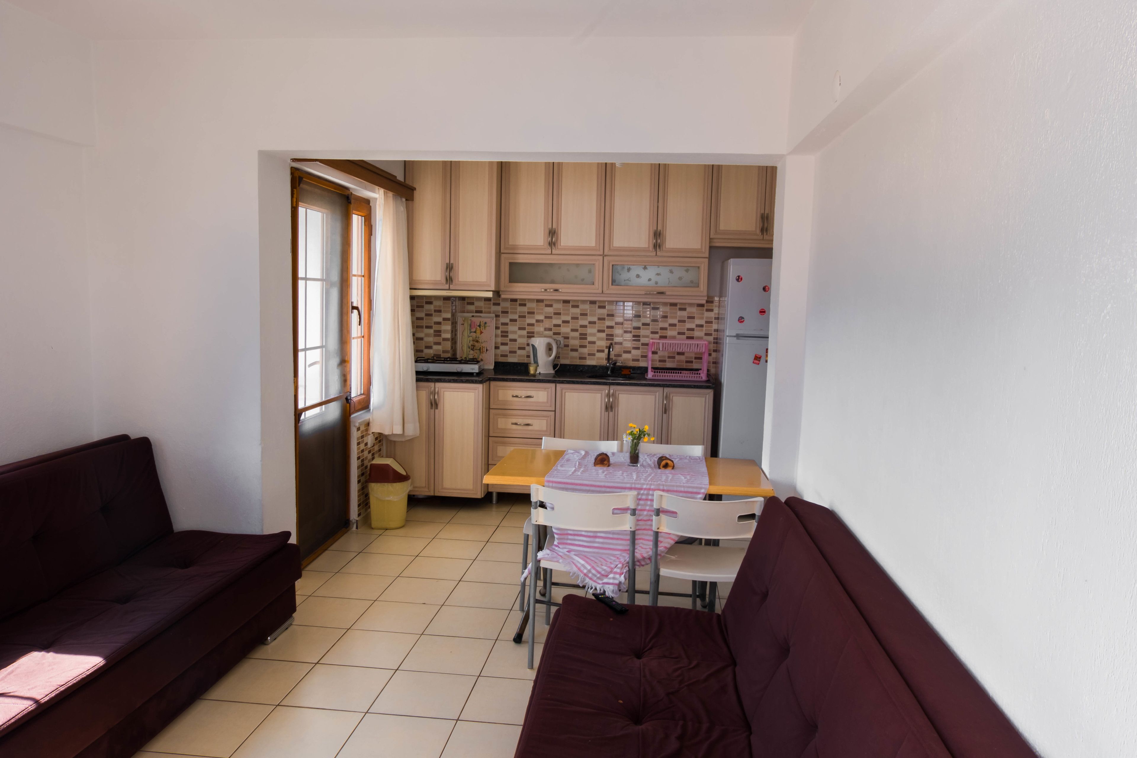 A compact living space with a kitchenette, a dining area with a table and chairs, and a sofa.