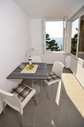 Un petit balcon avec une table et des chaises, une bouteille de vin et un verre.