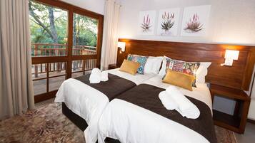 A double bed with white and brown linens, a wooden headboard, and two wall-mounted lamps.