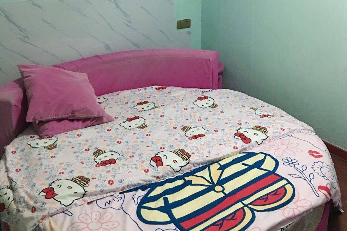 Un dormitorio con cama, aire acondicionado de pared y pared de color azul claro.