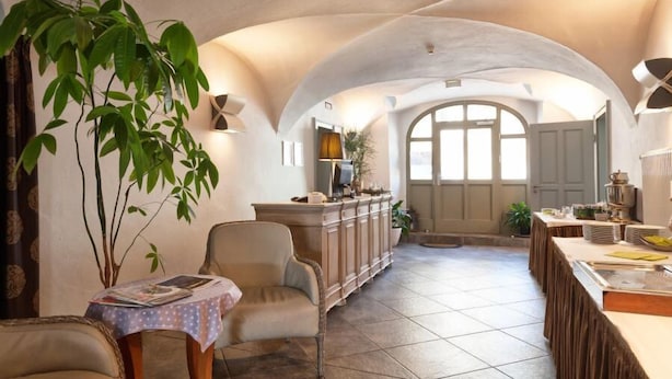 A spacious room with a high arched ceiling, a dining area with a long table, and a seating area with a sofa and a small table. - DECKERT'S HOTEL AM KATHARINENSTIFT (Lutherstadt Eisleben)