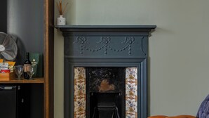 A room with a fireplace, a framed picture above it, a wooden bench, and a carpeted floor.