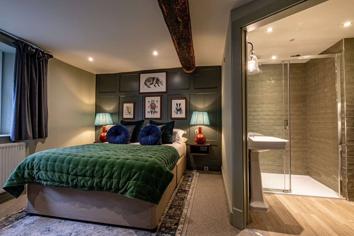 Un dormitorio con cama, lámparas de noche, mesita de noche y un cuadro enmarcado en la pared.