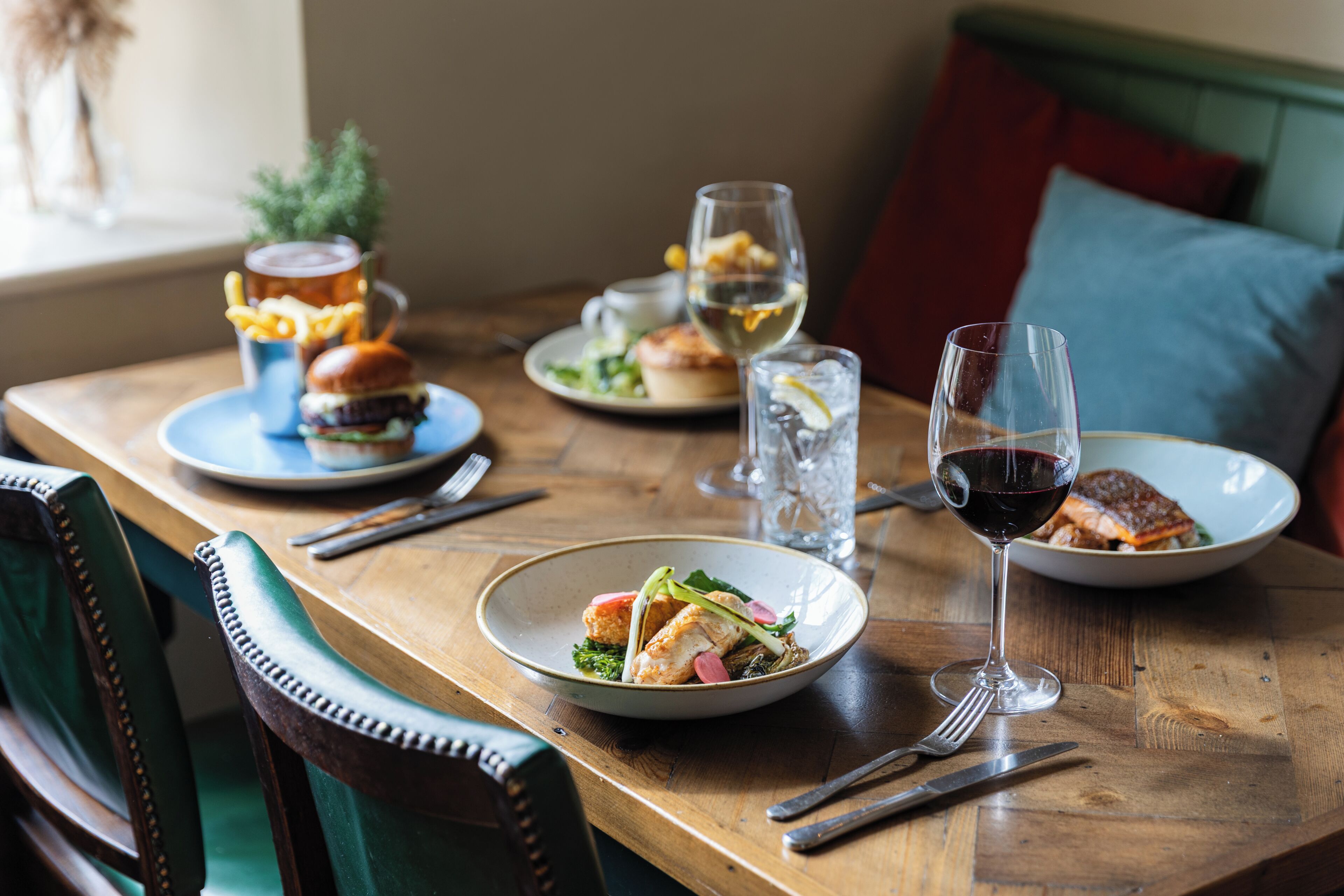 Une table à manger dressée avec des assiettes remplies de nourriture, des verres contenant des boissons et des couverts.