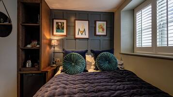 Un dormitorio con una cama grande, una mesita de noche, una lámpara y cuadros en la pared.