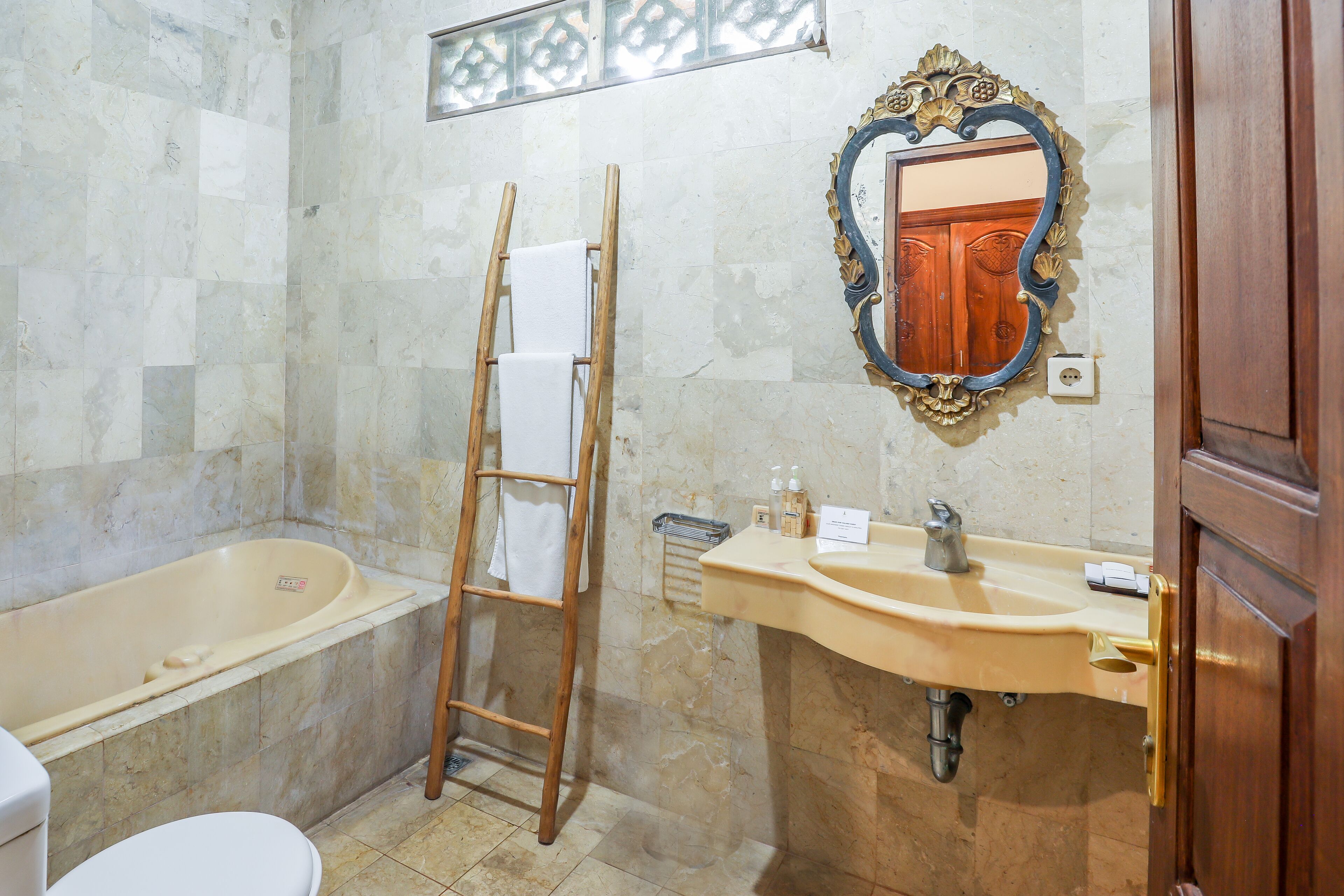 Une salle de bain avec une baignoire, une échelle en bois, un lavabo et un miroir.