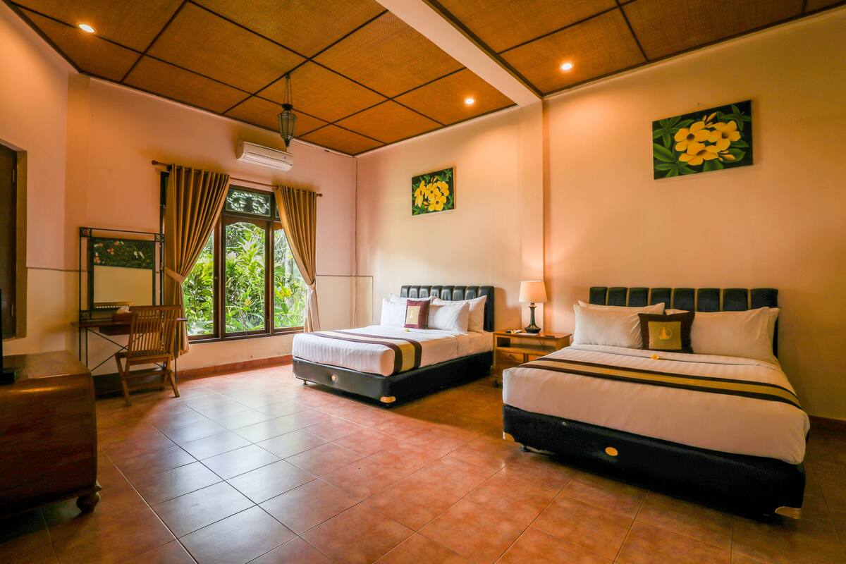 A hotel room with two beds, a desk, a chair, and a window with curtains.