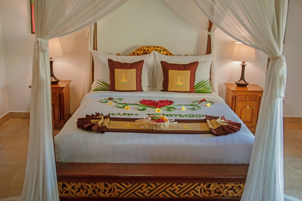 A bed with a canopy, a bedside table, and a nightstand.