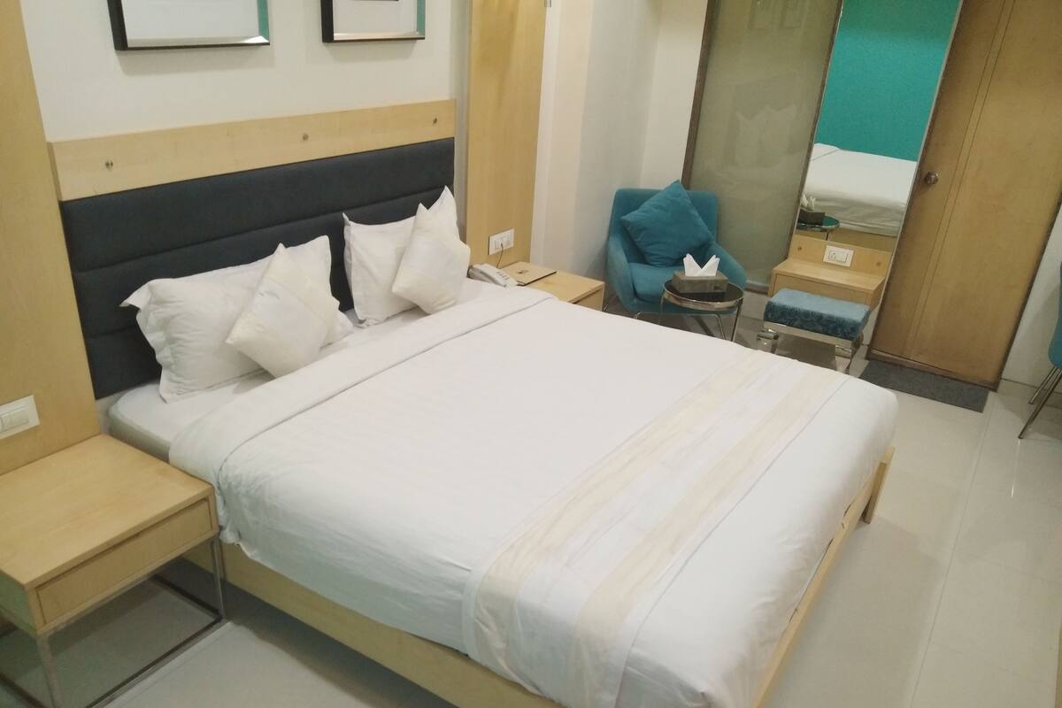 A neatly made bed with white bedding, a wooden headboard, and a bedside table with a lamp.
