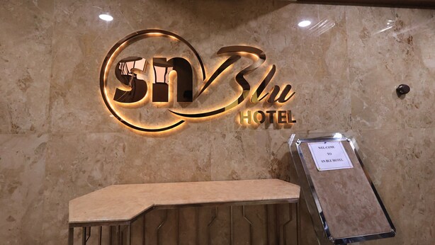 A hotel reception area with a marble wall and a reception desk. - Hotel SN Blu (Ahmedabad)