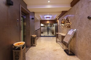 A hotel lobby with a marble floor, a reception desk, a glass door entrance, and a signboard. - Hotel SN Blu (Ahmedabad)
