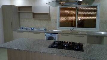 Una cocina moderna con encimera de granito, electrodomésticos de acero inoxidable y ventana con persianas.
