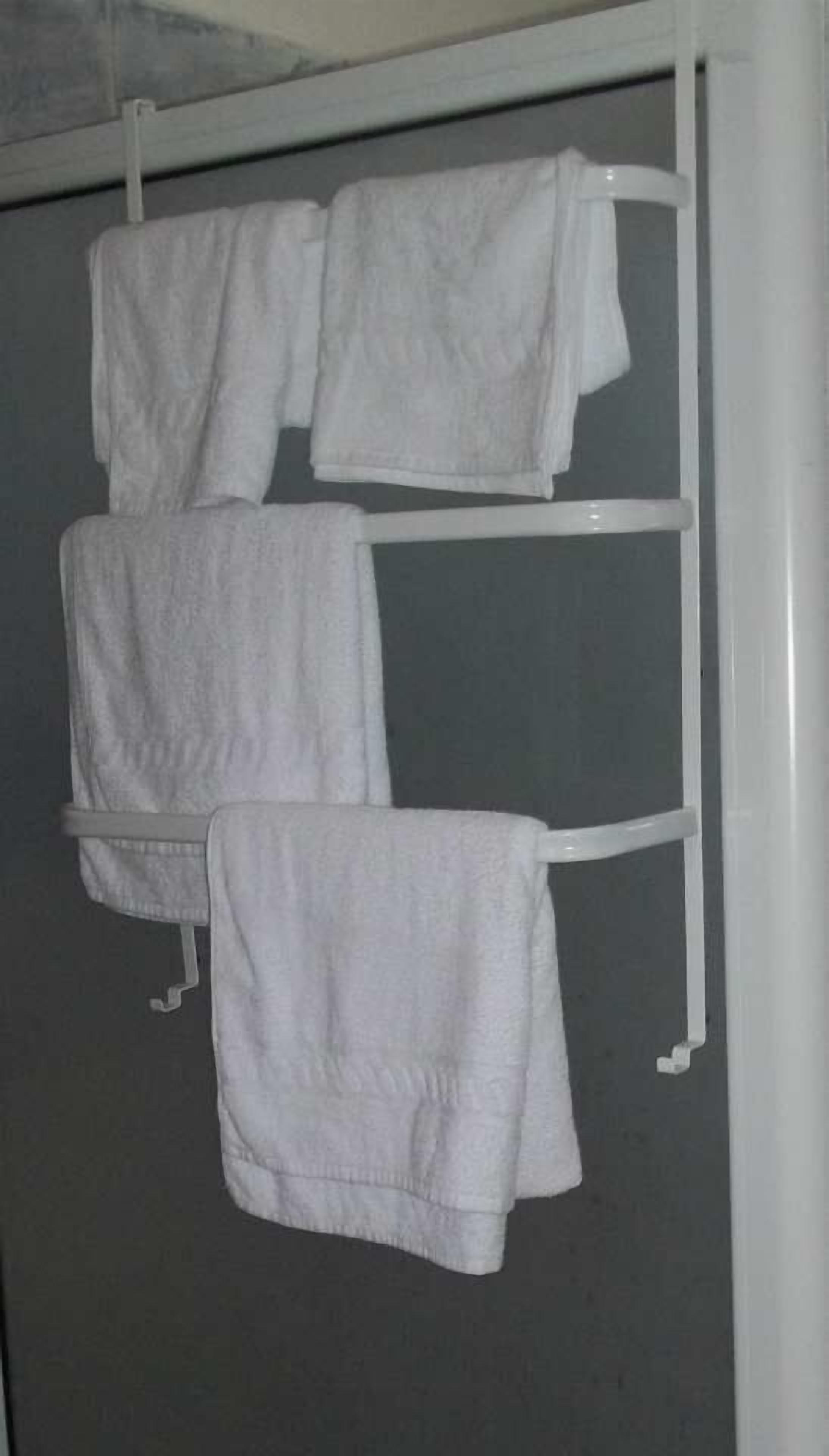 A white towel rack with three white towels hanging on it.