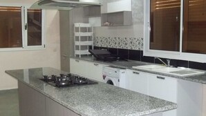 Una cocina moderna con encimera de granito, electrodomésticos de acero inoxidable y lavavajillas integrado.