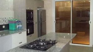 Una cocina moderna con encimera de granito, electrodomésticos de acero inoxidable y una puerta corrediza de vidrio que da a un balcón.
